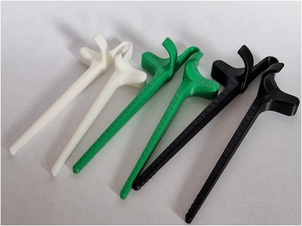 Five plastic medical or utility tools with long shafts and curved ends, shown in white, green, and black on a light gray background.